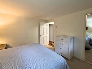 A bedroom with a bed, a dresser, and a door leading to another room. - Cozy Mountain Condo Near Sugar Mountain Ski Resort (Sugar Mountain)