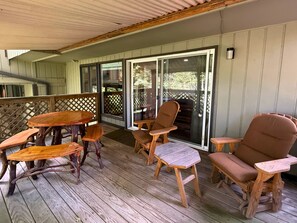 A wooden deck with a table and chairs, a sliding glass door leading to an outdoor area, and a wooden railing. - Cozy Mountain Condo Near Sugar Mountain Ski Resort (Sugar Mountain)