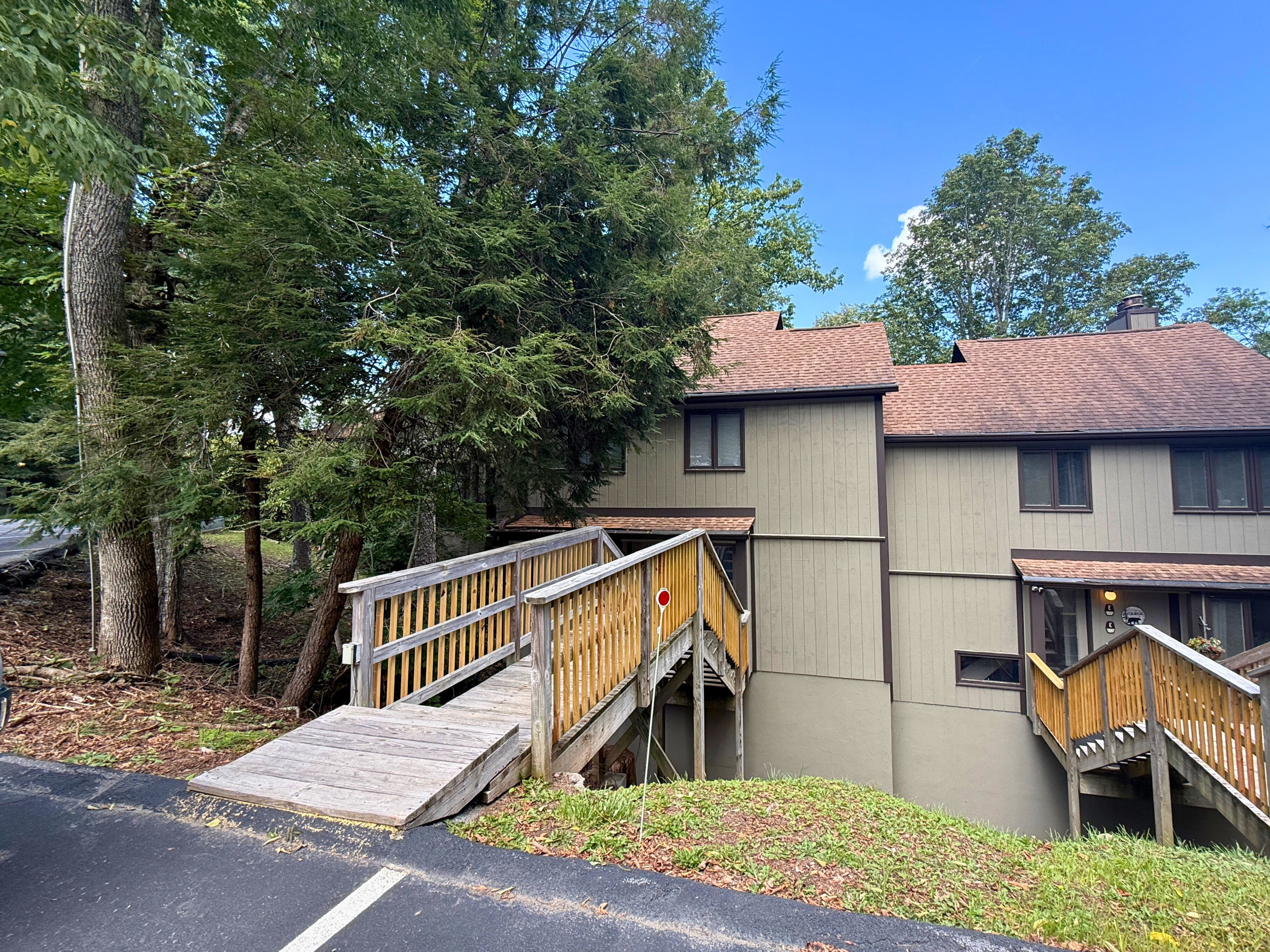 A two-story building with a wooden deck and stairs leading to the entrance.