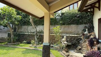 A covered patio area with a stone wall, a small rock garden, and a wooden bench.