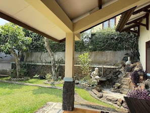 Un patio cubierto con un muro de piedra, un pequeño jardín de rocas y un banco de madera.