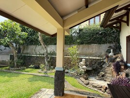 Un patio cubierto con un muro de piedra, un pequeño jardín de rocas y un banco de madera.