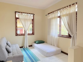 Una habitación con cama, sofá y ventana con cortinas.