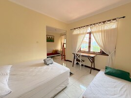 Una habitación con dos camas, un escritorio y una ventana con cortinas.