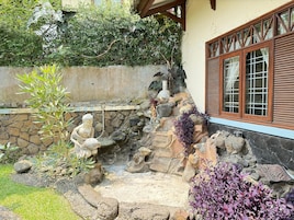A garden with a stone wall, a statue, and various plants.
