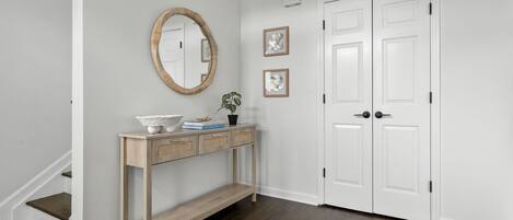 A hallway with a wooden console table, a white door, and a staircase.