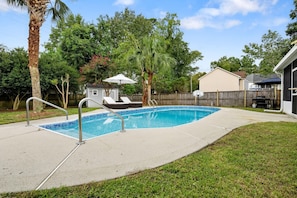 A residential backyard with a swimming pool, a small deck, and a barbecue area. - The Chantrell Pool Hot Tub Pets (North Charleston)
