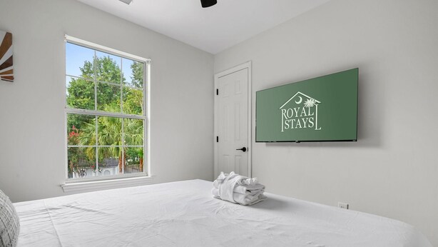 Een hotelkamer met een groot bed, een raam met uitzicht op bomen en een aan de muur bevestigd bordje voor Royal Stays.