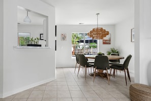 A modern dining area with a round table, six chairs, and a hanging light fixture. - The Chantrell Pool Hot Tub Pets (North Charleston)