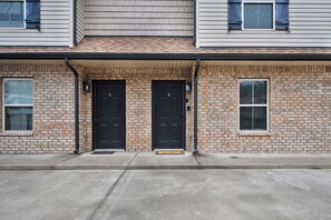 A two-story building with brick facade, two black doors, and a small window with shutters. - Smithson Getaway-Wi-Fi|King Bed | Desk | Private Bath in Each Room (Clarksville)