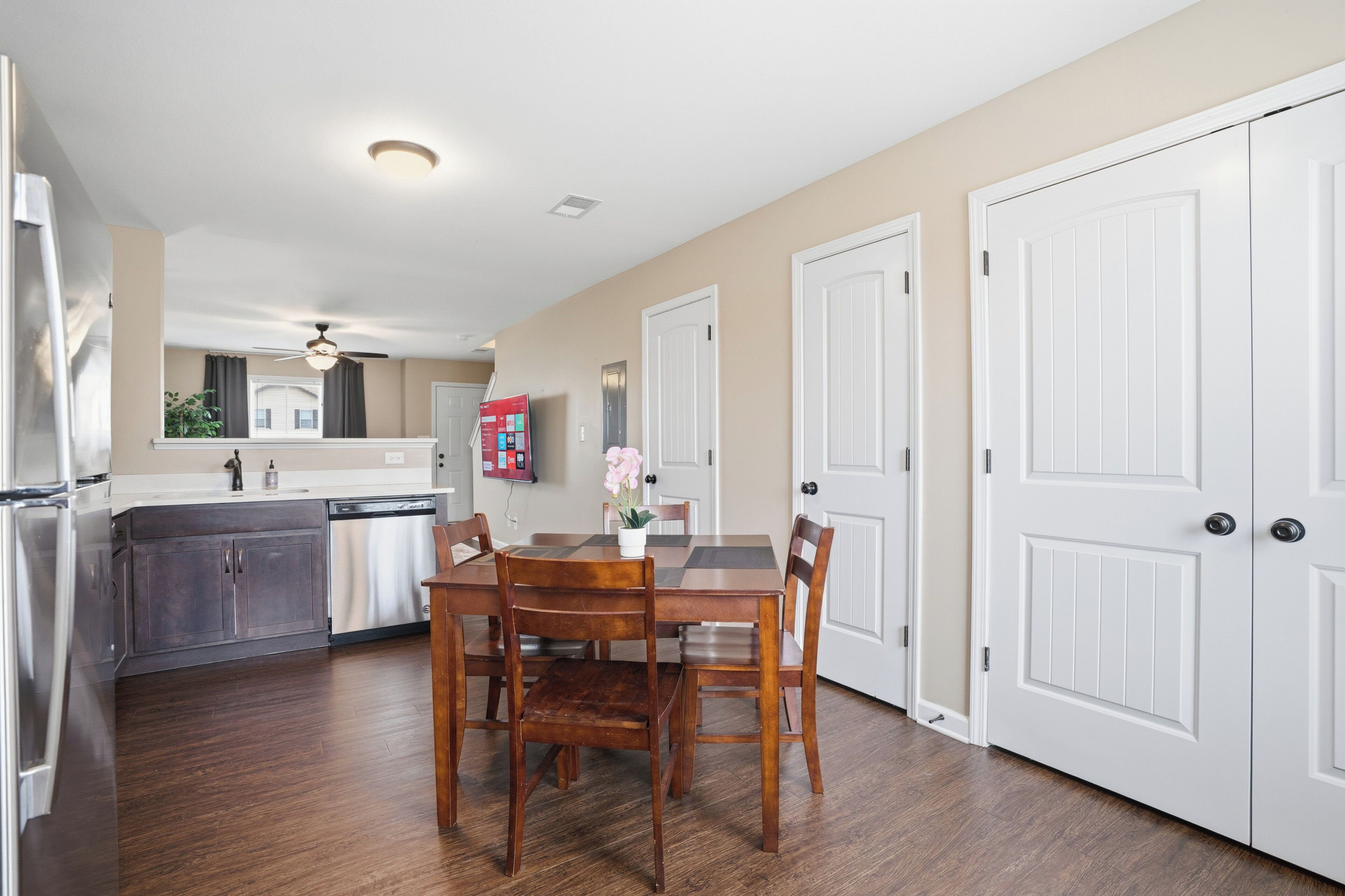 A modern kitchen with a dining area, wooden chairs, and a white refrigerator.