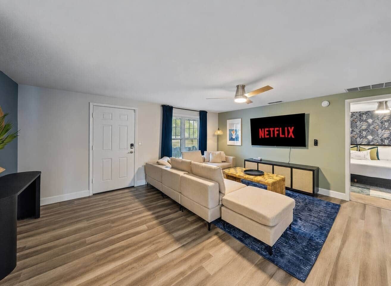 Een moderne woonkamer met een bank, een salontafel en een flatscreen televisie aan de muur.