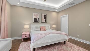 A bedroom with a bed, bedside tables, a ceiling fan, and two wall-mounted artworks.