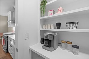A kitchenette with a coffee maker, a kettle, and a coffee cup on the counter. - Pink Dream House | Game Room | Separate Loft Suite | 2mi to Raleigh (Raleigh)