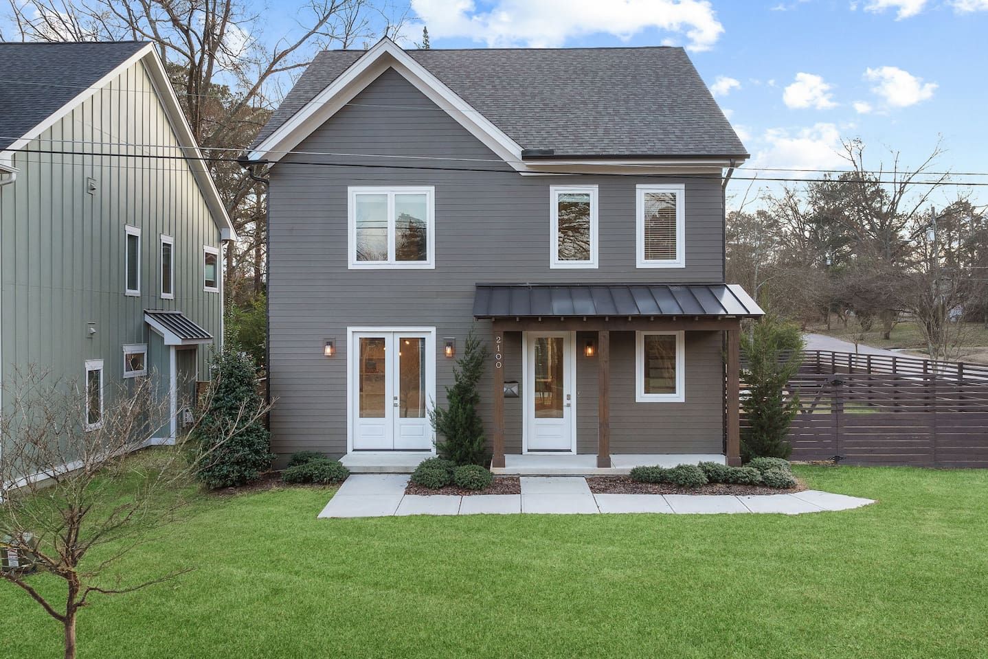A two-story house with a front porch, a garage, and a fenced yard.