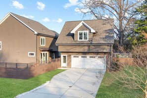 A two-story residential house with a visible garage door, a driveway, and a well-maintained lawn. - Pink Dream House | Game Room | Separate Loft Suite | 2mi to Raleigh (Raleigh)