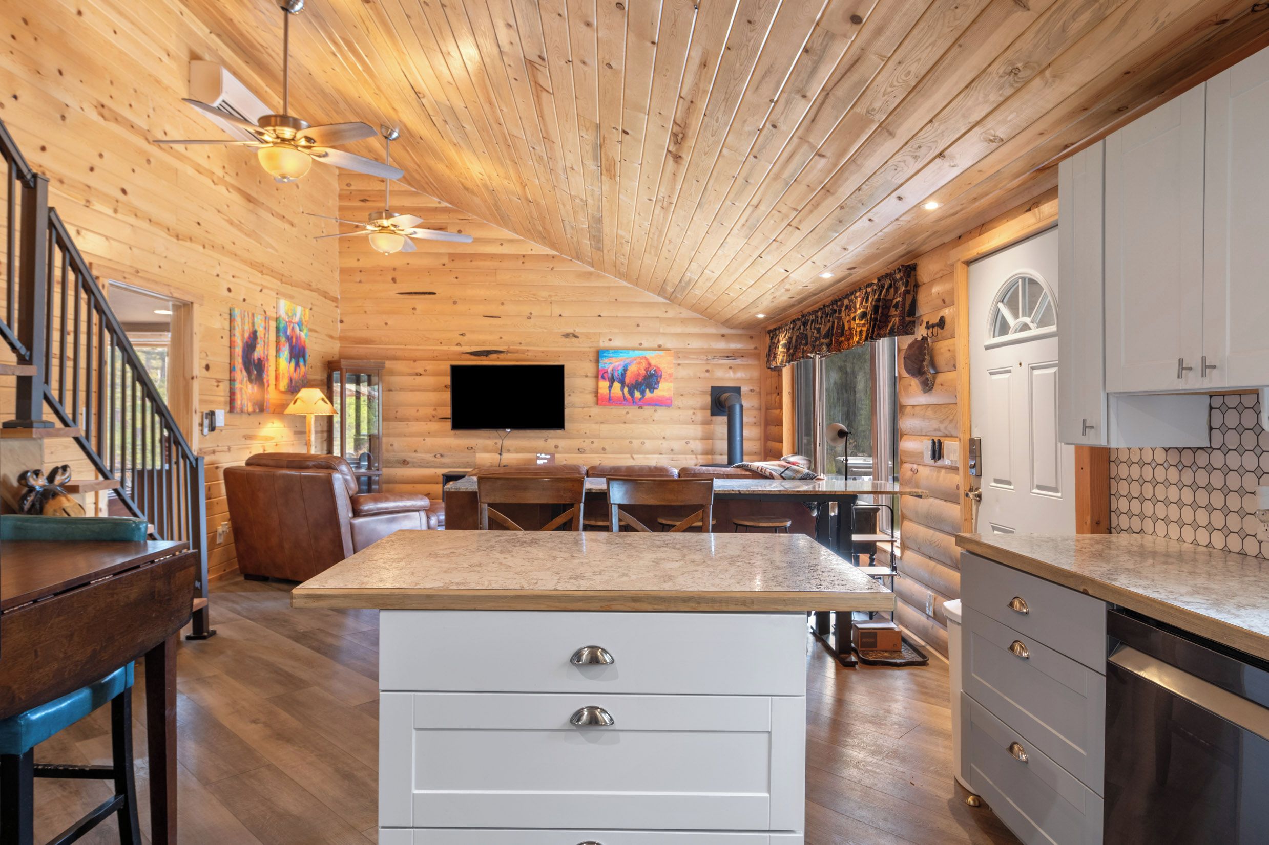 A modern log cabin interior with a kitchen, dining area, and a living room with a fireplace.