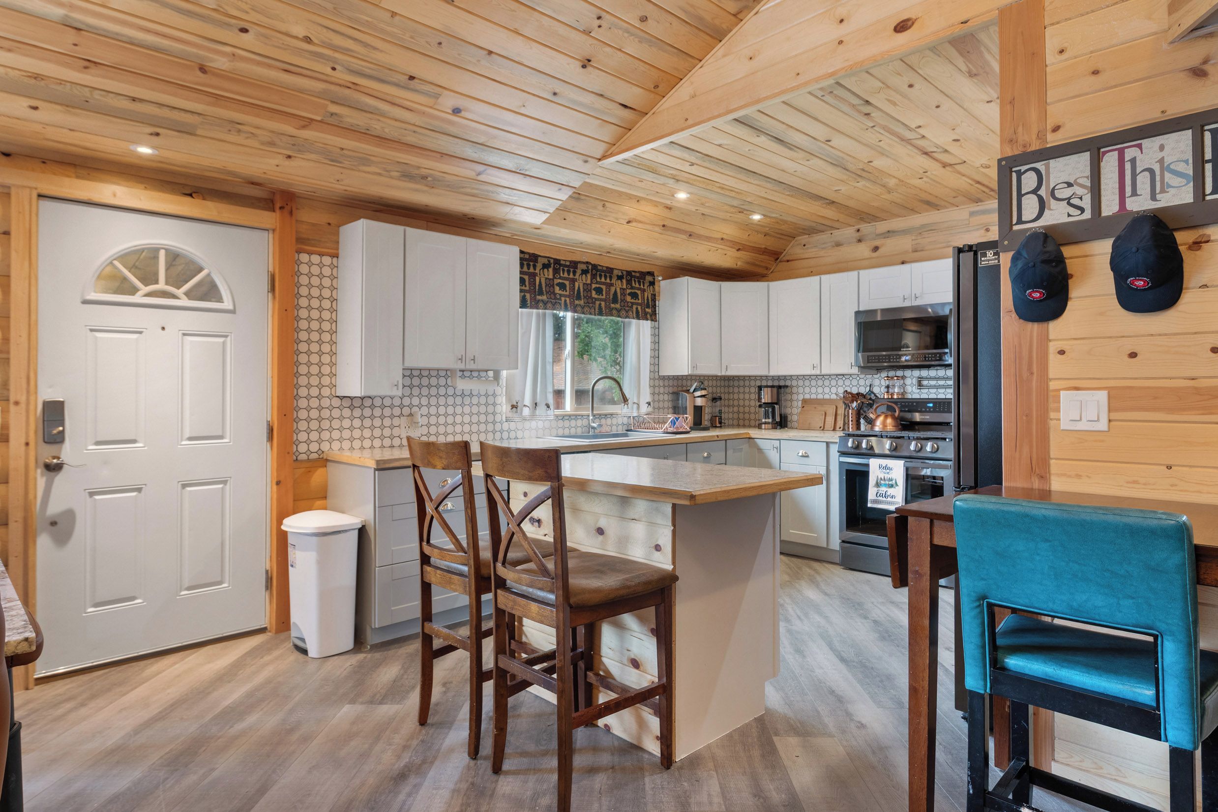 Une cuisine avec des meubles de rangement en bois, un îlot central et un coin repas avec des chaises.