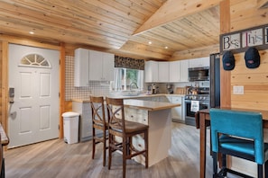 A kitchen with wooden cabinets, a central island, and a dining area with chairs.