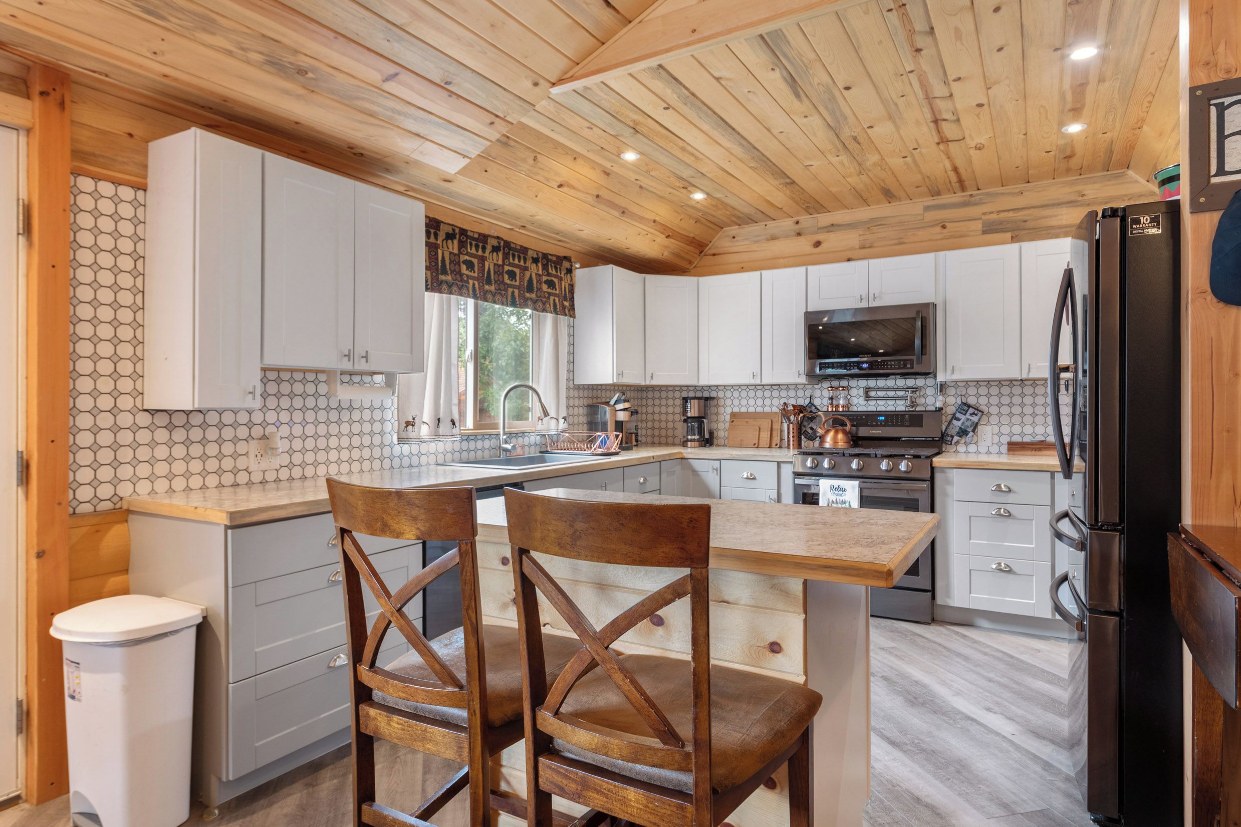 A modern kitchen with wooden cabinets, a central island, and stainless steel appliances.