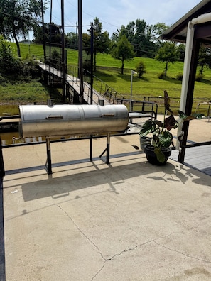 Un espacio exterior de concreto con una parrilla metálica, una planta en maceta y una cerca de metal.