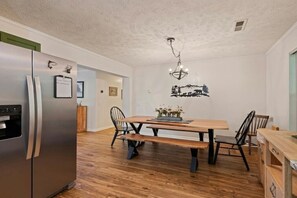 Eine moderne Küche mit einem Edelstahl-Kühlschrank, einem Holzespeisetisch und Stühlen.