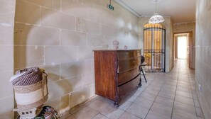 A hallway with a wooden cabinet, a basket, and a decorative lamp. - Stone Apt in Nadur | Terrace & Patio | Sleeps 6 (Nadur)