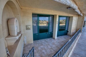 A building entrance with a stone facade, a green door, a mailbox, and a metal railing. - Stone Apt in Nadur | Terrace & Patio | Sleeps 6 (Nadur)