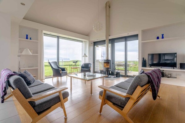 A spacious living room with a large window, a fireplace, a television, and a dining area.