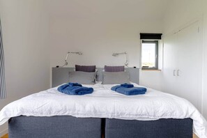 Een slaapkamer met een bed, twee bedlampjes, een raam en een garderobe.
