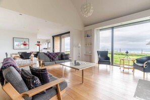 Een ruime woonkamer met een groot raam, een eethoek en uitzicht op de omgeving.