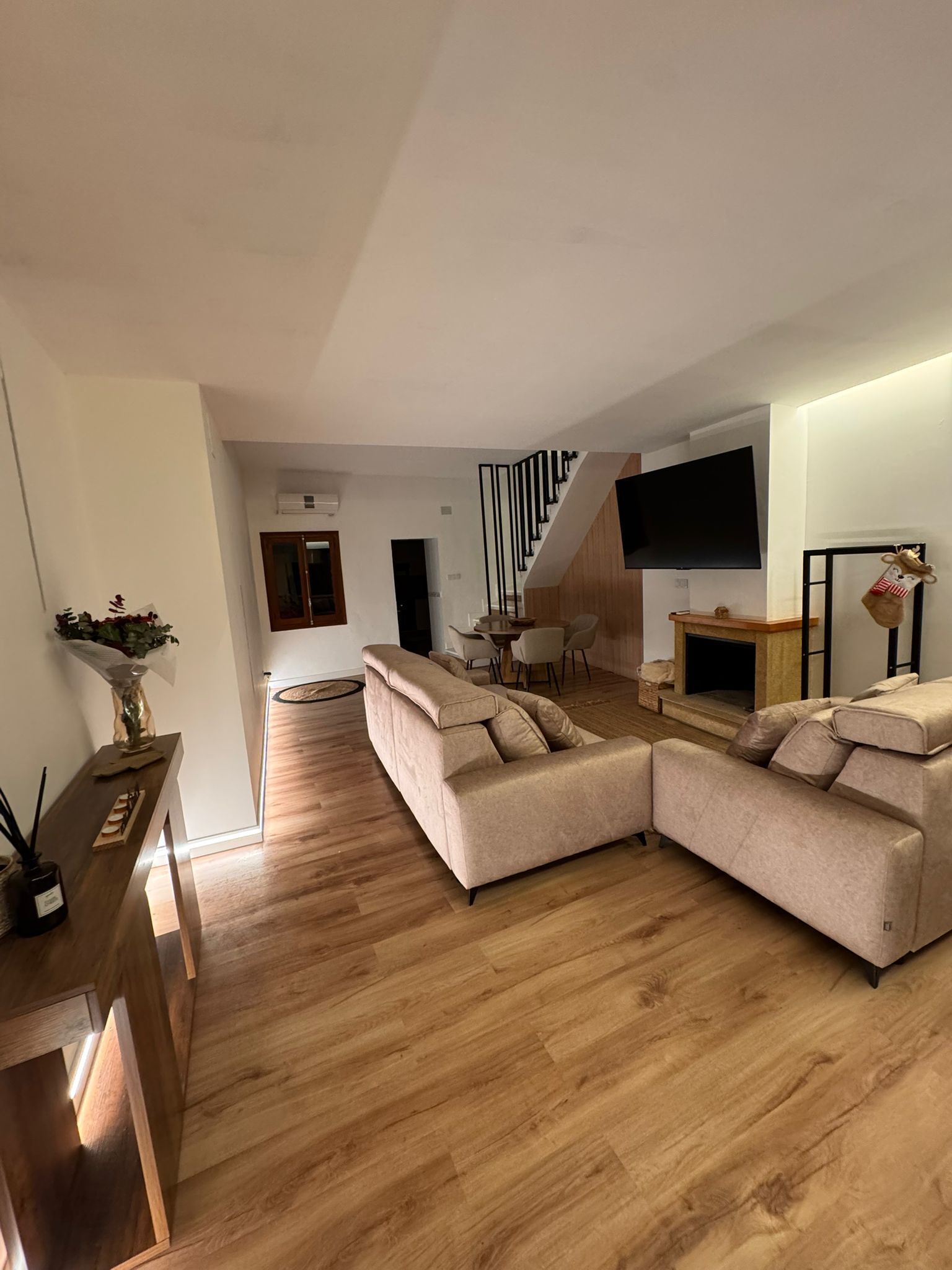 Una sala moderna con un sofá seccional, un televisor de pantalla plana y una chimenea.
