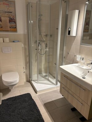 Een moderne badkamer met een douchecabine van glas, een toilet en een wastafel met spiegel.