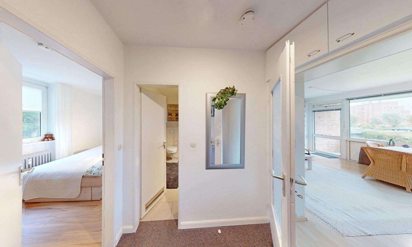 Un couloir donnant sur une chambre avec un lit, une salle de bain et une fenêtre offrant une vue.