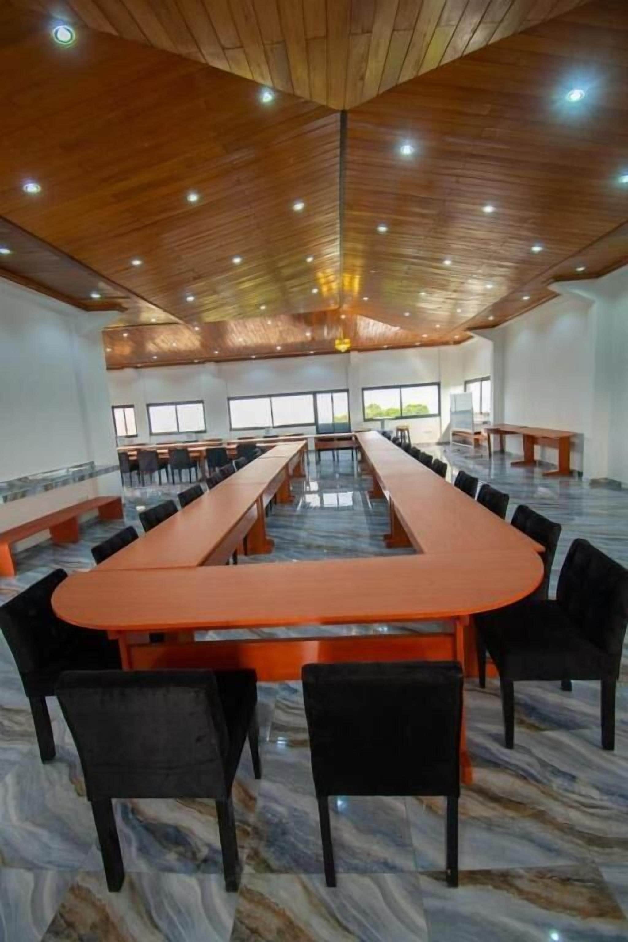 Una sala conferenze con un lungo tavolo e sedie, soffitto in legno e ampie finestre.