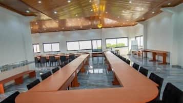 Una sala conferenze con un lungo tavolo e sedie, soffitto in legno e ampie finestre.
