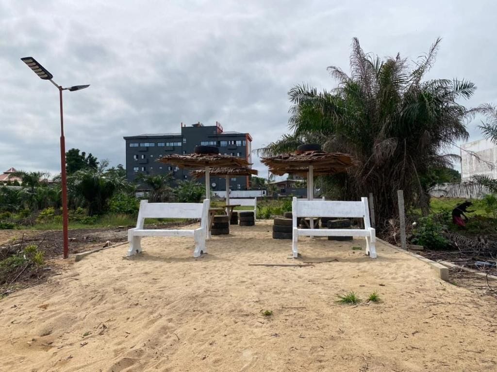 Une zone sablonneuse avec des bancs blancs et un palmier.