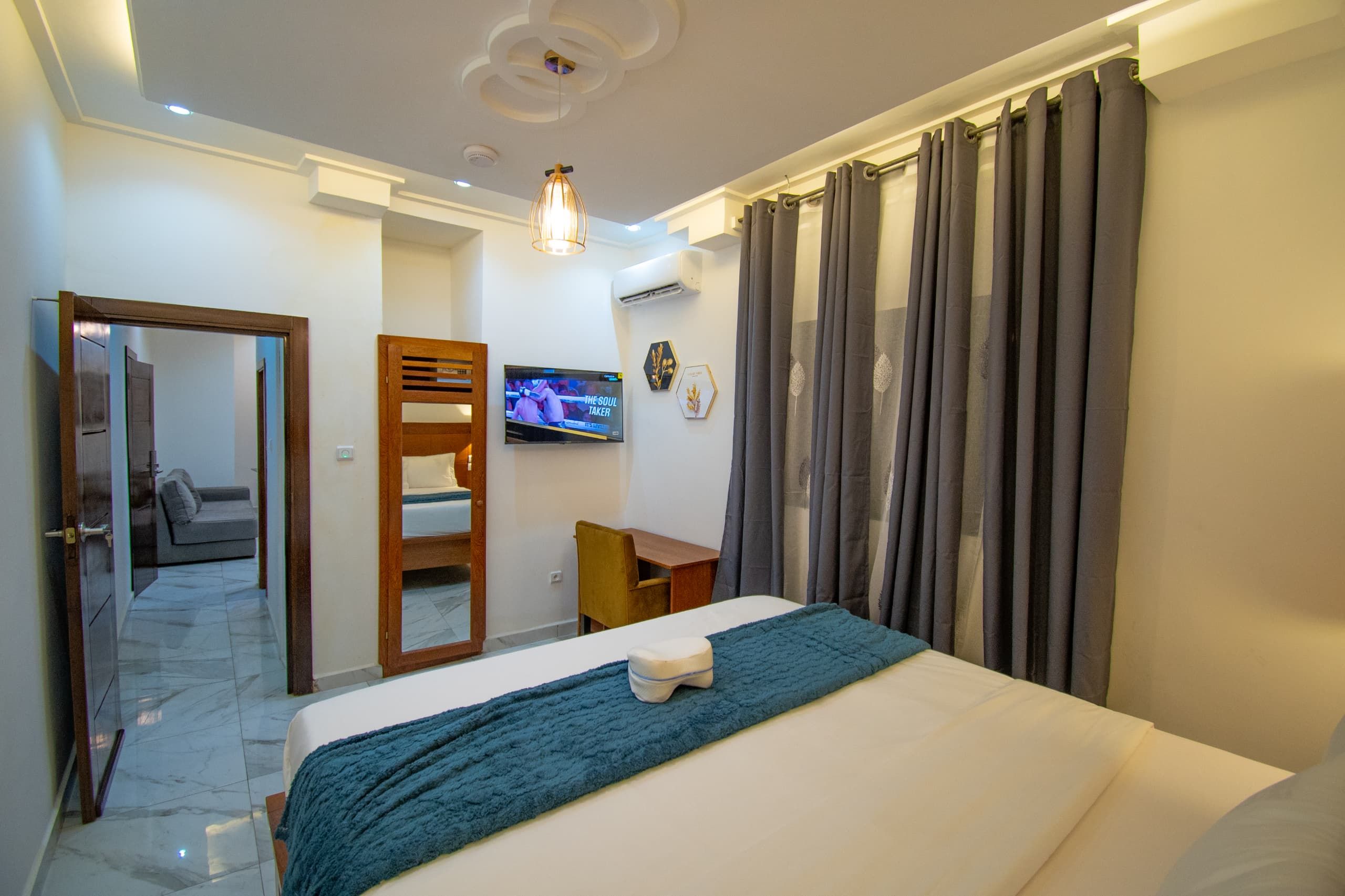 Una habitación de hotel con una cama, un escritorio, un televisor y una puerta que da a un balcón.