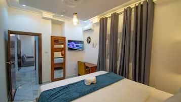 Una habitación de hotel con una cama, un escritorio, un televisor y una puerta que da a un balcón.