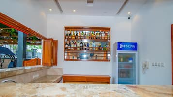 A bar area with a marble countertop, a wooden shelf with various bottles, and a blue refrigerator with the logo 'INOVA'.