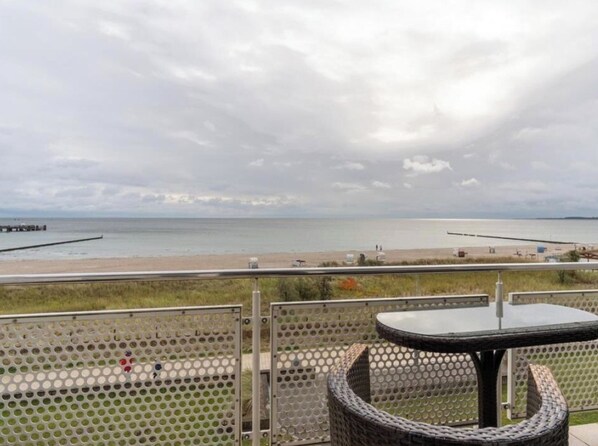 Ein Balkon mit Blick auf Strand und Meer.