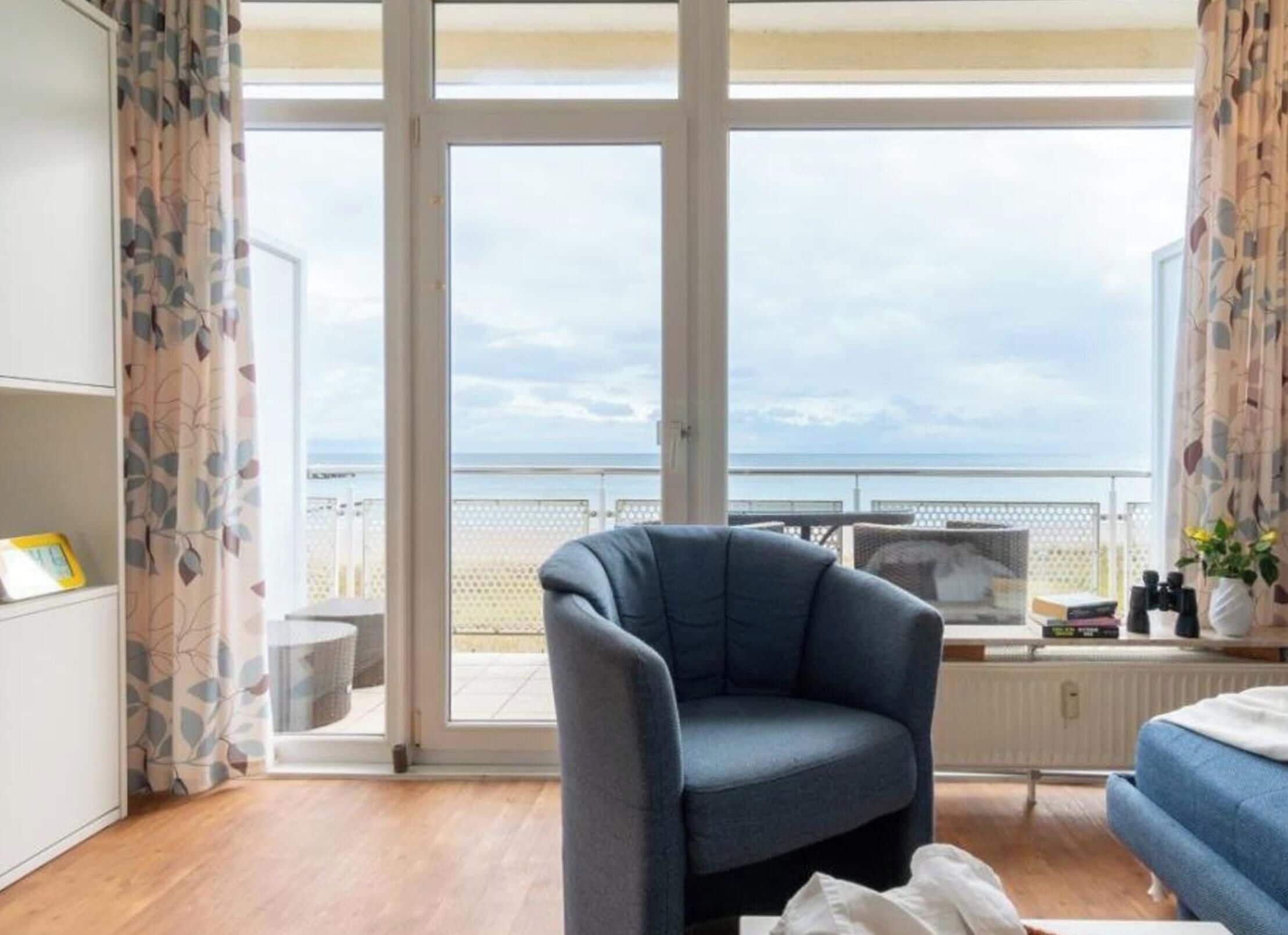 A room with a large sliding glass door leading to a balcony with a view of the sea.