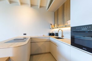 A modern kitchen with a built-in oven, a sink, and a countertop. - Sapphire at The Reef - Ocean View Penthouse (Sint Michiel)