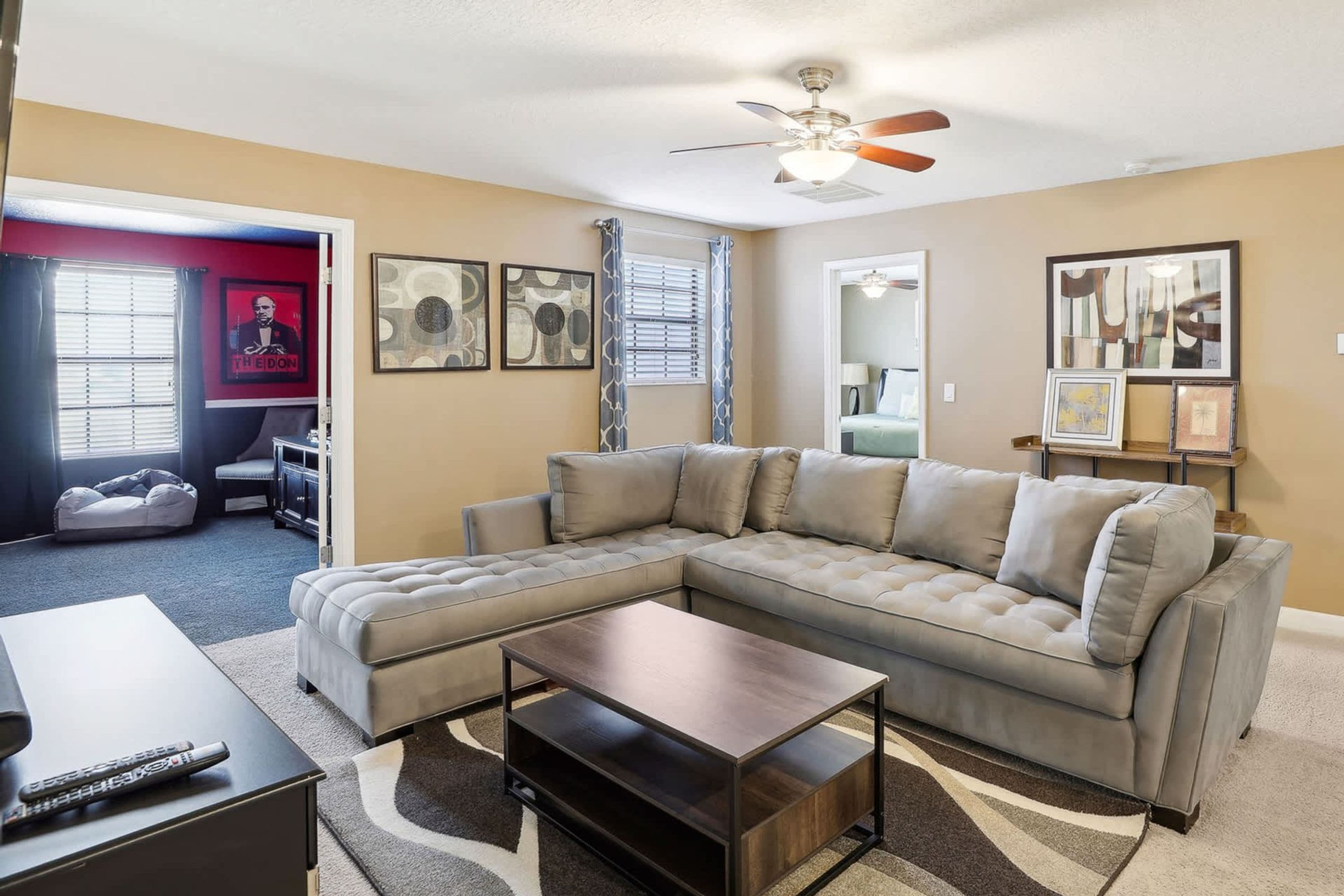 A living room with a sectional sofa, a coffee table, and artwork on the walls.