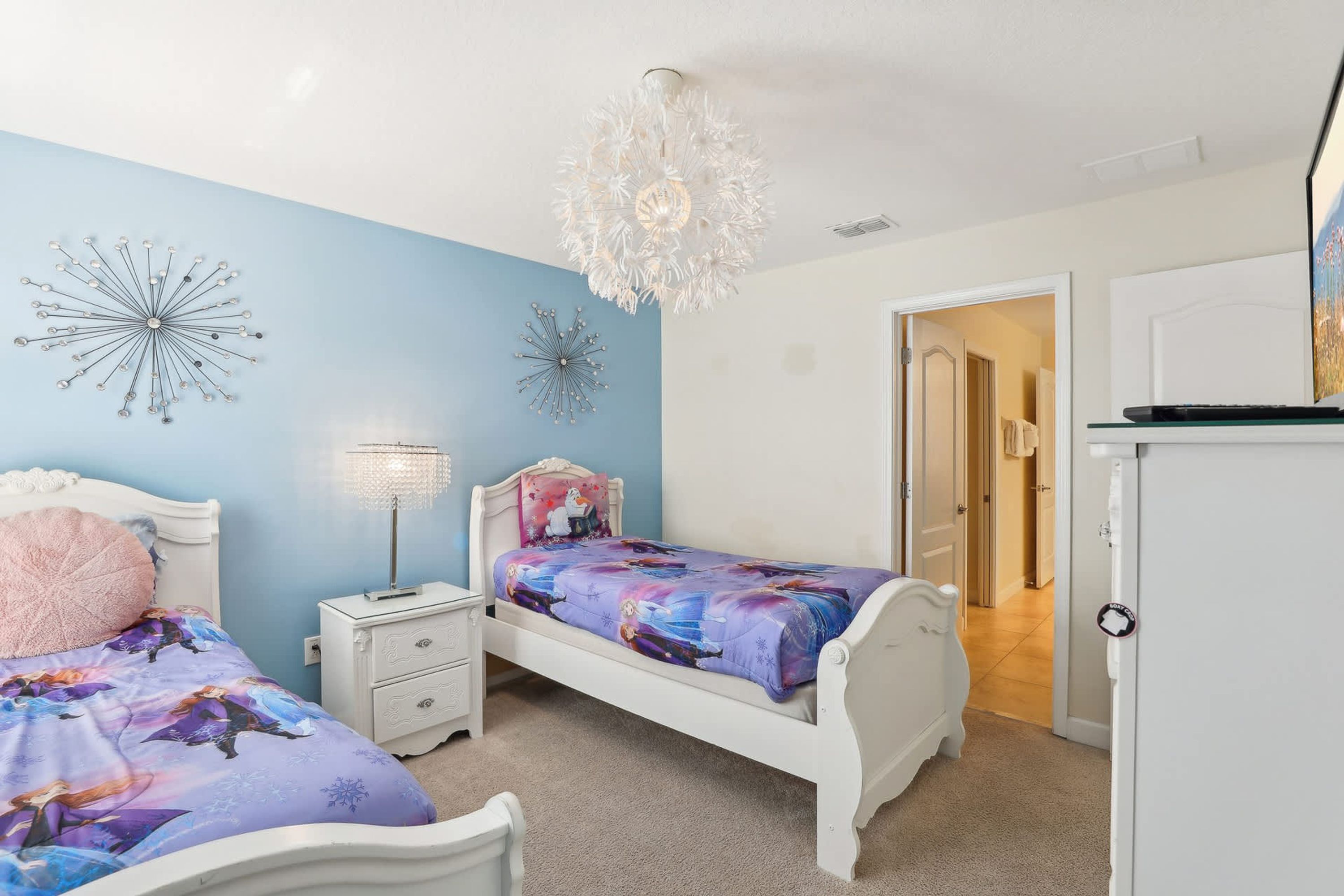 Een slaapkamer met twee bedden, een kroonluchter en wanddecoratie.