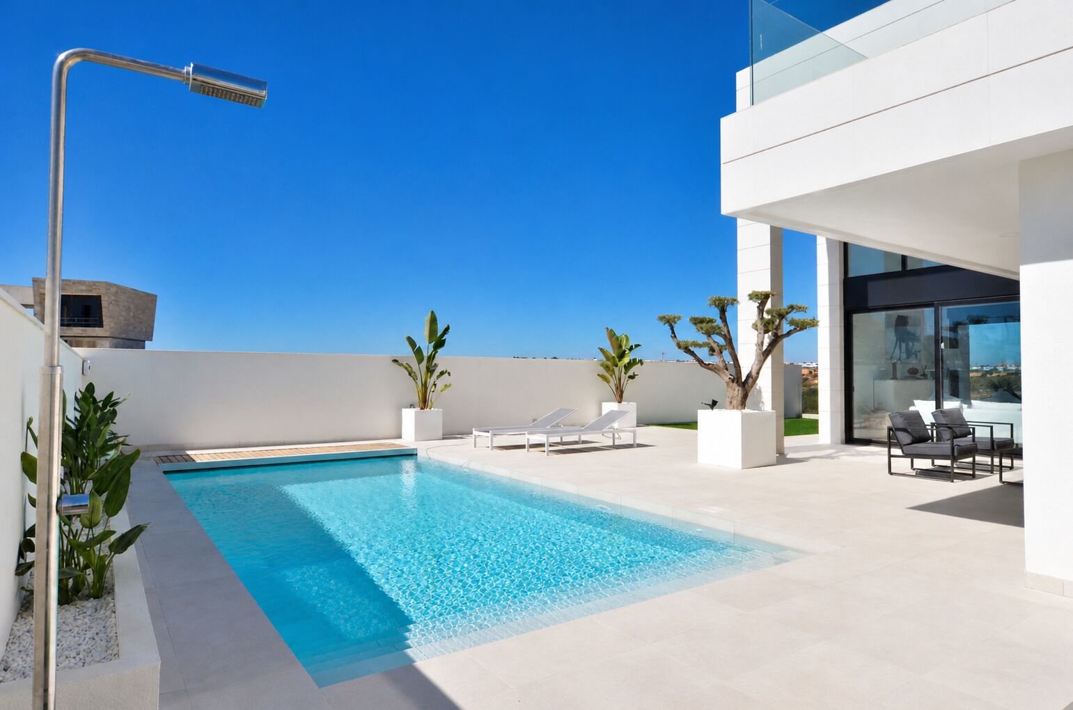 Een modern buitenzwembad met helderblauw water, ligbedden en plantenpotten.
