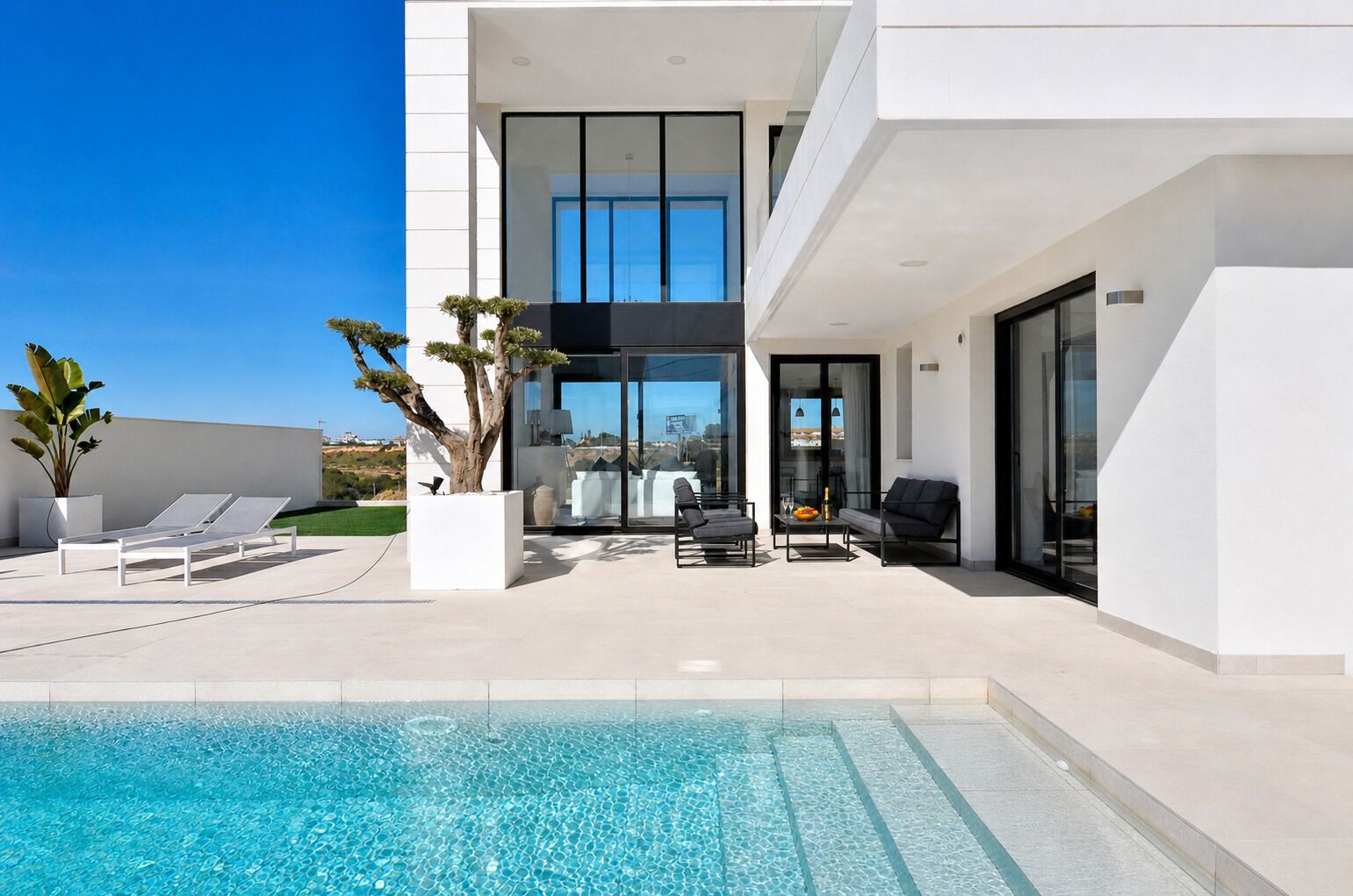 Une maison moderne dotée d’une piscine, d’un espace salon extérieur et offrant une vue sur le paysage.