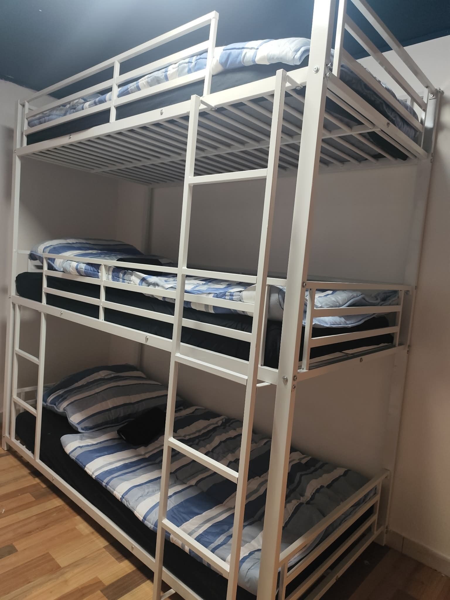 A bunk bed with three levels, each with a mattress and pillows.