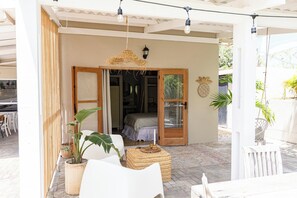 An outdoor seating area with wicker furniture, a potted plant, and a woven stool. - New stylish studio in the heart of Willemstad (Willemstad)