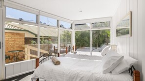 Ein Schlafzimmer mit großem Fenster, einem Bett und Blick auf einen Garten.